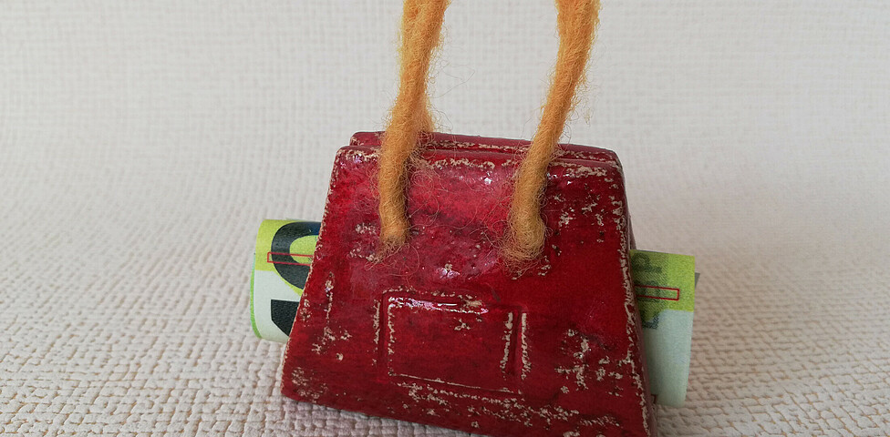 Eine aus Ton gefertigte Tasche mit einem 100-Euro-Gelschein in ihr.