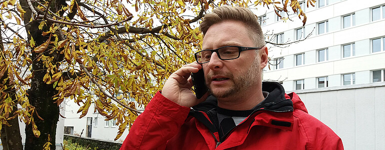 Bereichsleiter Christian Eile mit der Caritas-Jacke telefoniert mit dem Handy im Katastrophen-Fall.