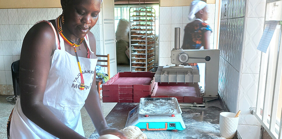 Eine Mitarbeiterin der Bäckerei knetet den Brotteig auf der Arbeitsfläche.