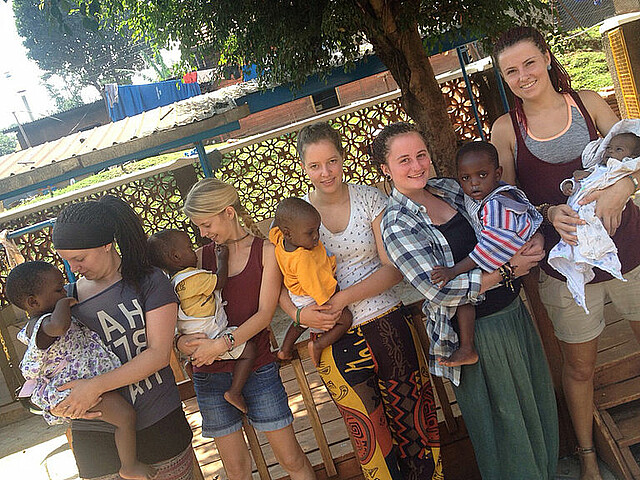 Viele Freiwillige die sich durch den Internationale Freiwilligeneinsatz in Afrika freiwillig engagieren, haben Kinder auf den Arm.