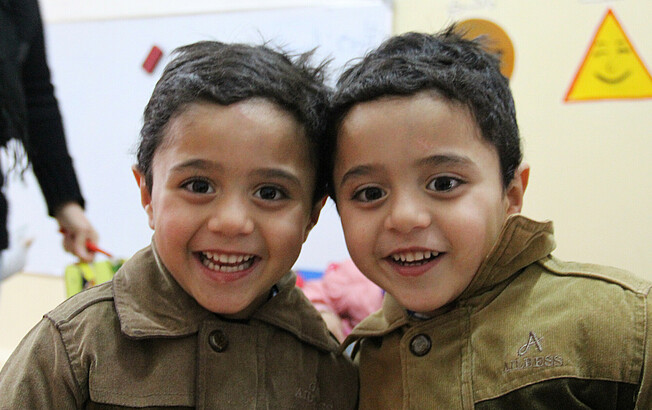 Zwillinge in Jordanien lächeln in die Kamera.